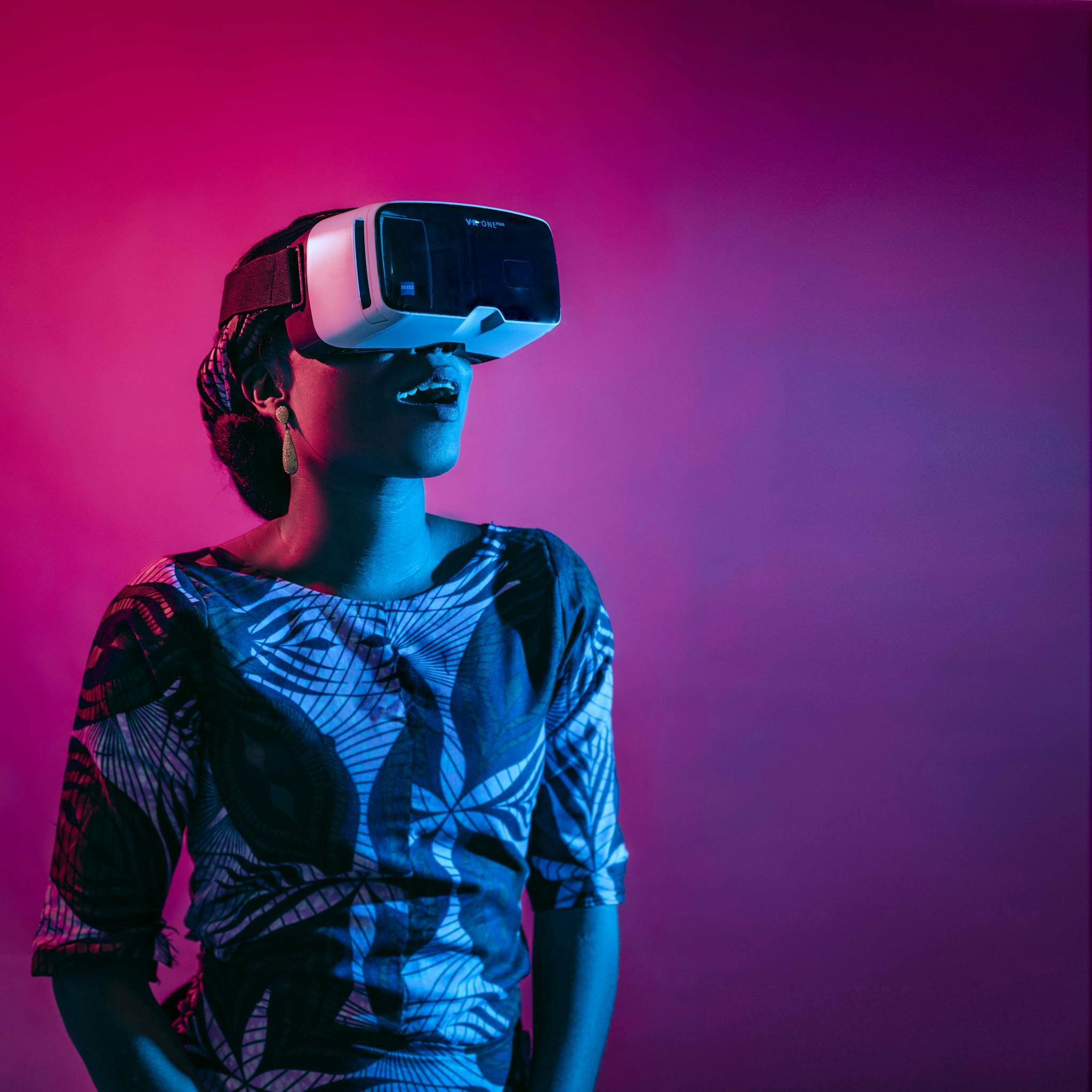 A woman enjoying a virtual reality experience with vibrant lighting indoors.